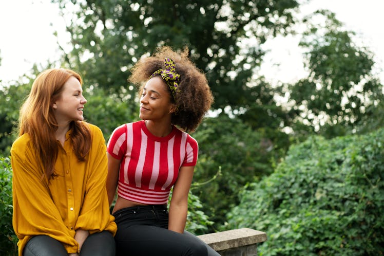 Biracial lesbian couple sitting on wall
