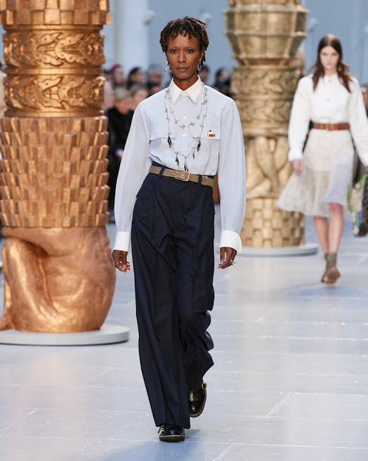 A model in a white button up shirt and black dress pants walks the runway at chloe's fall 2020 show