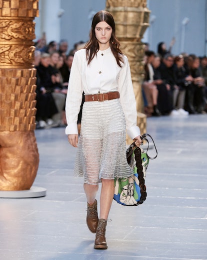 A model in a white top, sheer skirt, brown belt and colorful handbag walks the runway at chloe's fal...