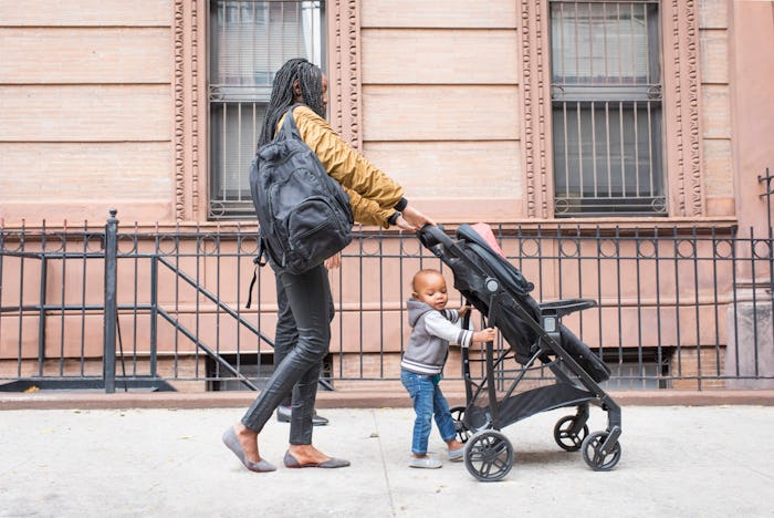 Mom pushing stroller, helped by toddler