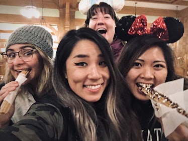 A big group of friends huddle together to snap a selfie with churros at Disneyland