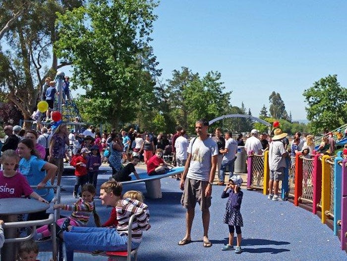 Children and parents play outside at a blue playground