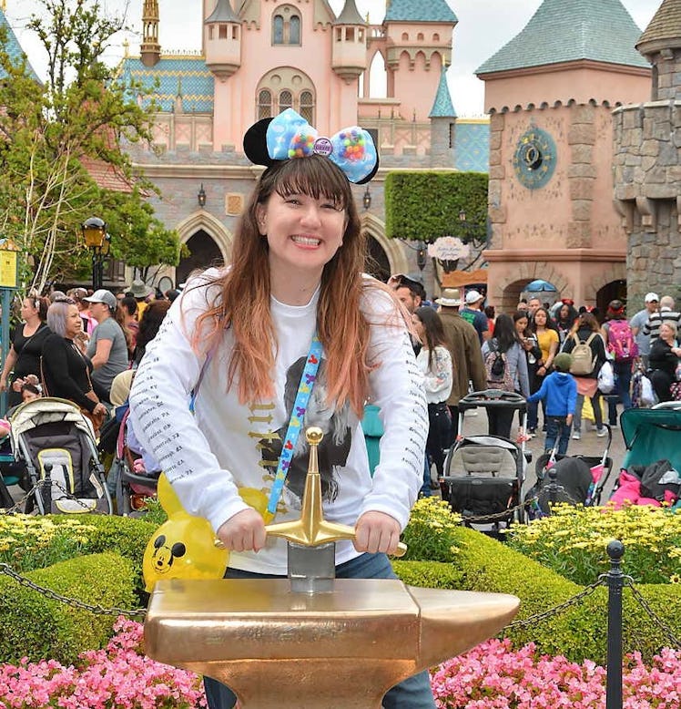 A woman tries to pull out the sword in the stone at Disneyland. 