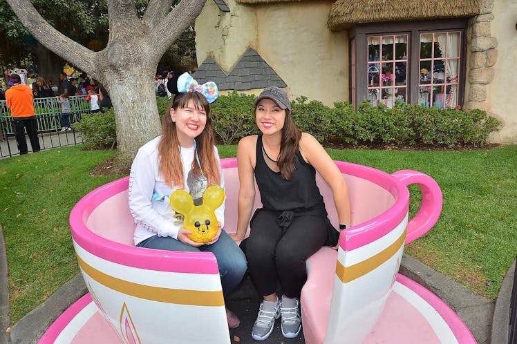 Two happy women sit in a pink tea cup at Disneyland from "Alice in Wonderland.'