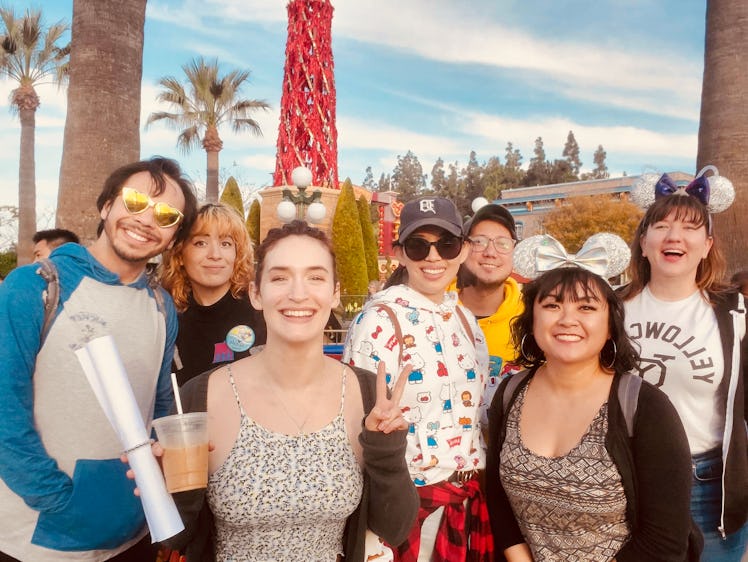 A big group of friends in Mickey Mouse ears smile and pose together at Disneyland.