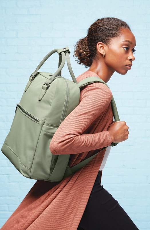 A woman carries a green backpack from Target's Open Story luggage brand.