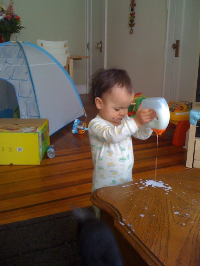 a toddler girl pouring glue on a table