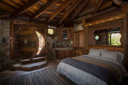 A secluded 'Hobbit' inspired home on Airbnb has lots of wood details and a bed right near the front ...
