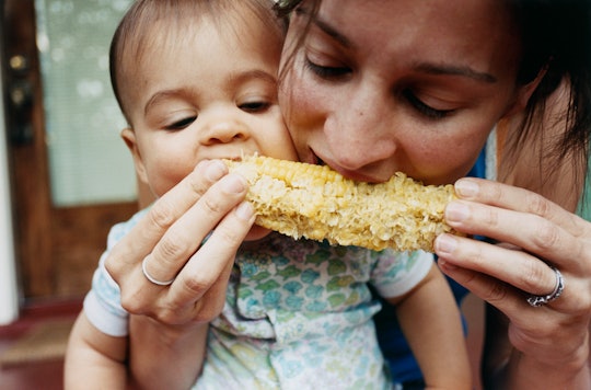 A mom and toddler share a corn cob
