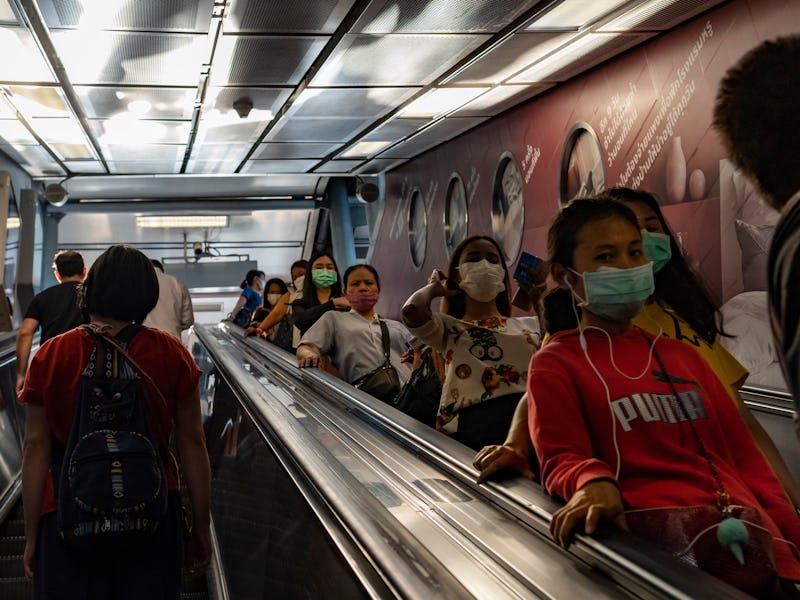 People walk while wearing protective face masks due to concern over the spread of coronavirus in Ban...