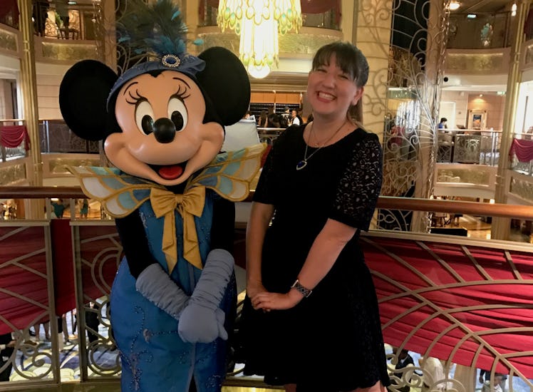 A woman and Minnie Mouse in formal wear pose in the atrium of the Disney Cruise ship. 