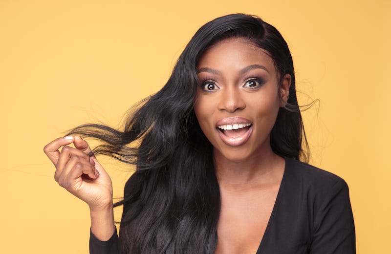 Influencer Patricia Bright grinning and holding a lock of hair.