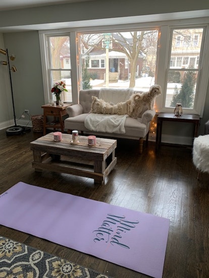 A living room with white furniture and a yoga mat on the floor