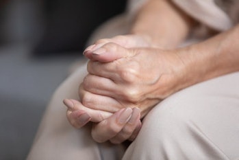 Close up unhappy lonely mature woman folded hands together, sitting on couch alone, upset desperate ...