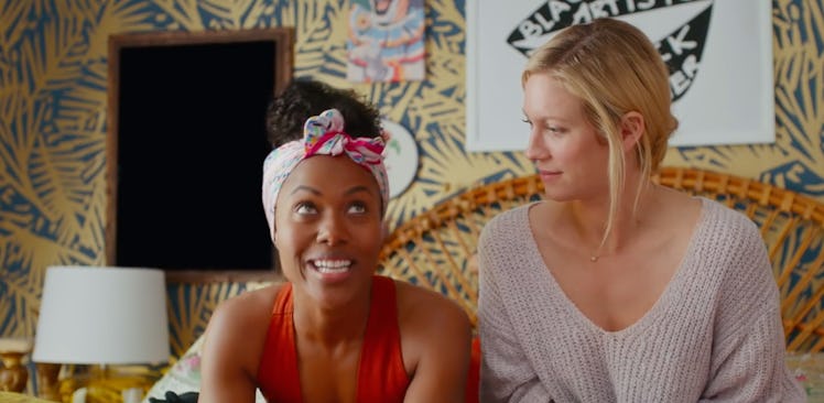 Two best friends sit on a bed in a colorful room and chat in 'Someone Great' on Netflix.
