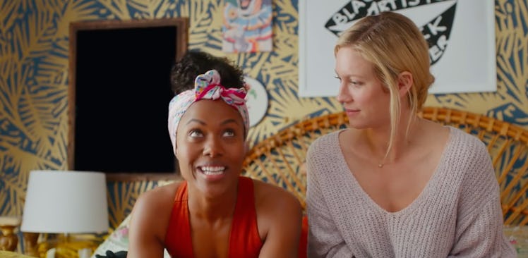 Two best friends sit on a bed in a colorful room and chat in 'Someone Great' on Netflix. 