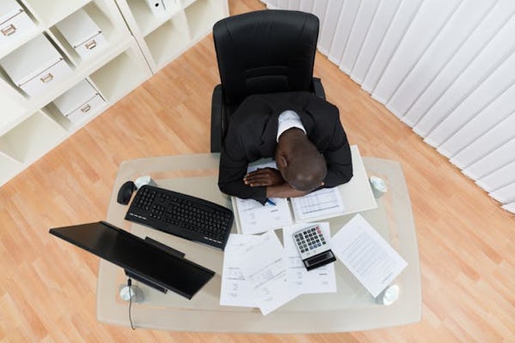 High Angle View Of Stressed Businessman Sleeping At Desk
