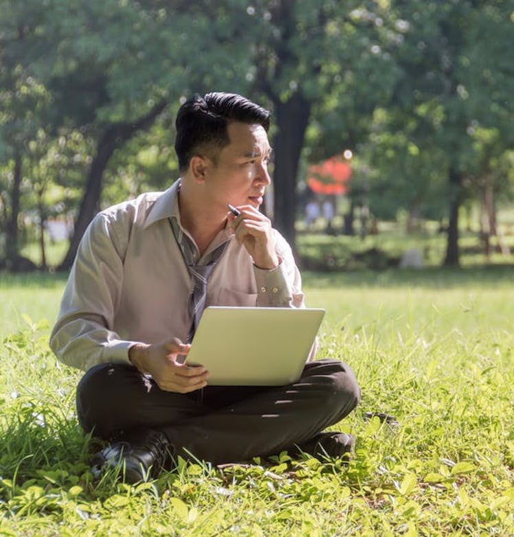 Businessman sitting on the lawn Using a notebook In researching information data analysis And planni...