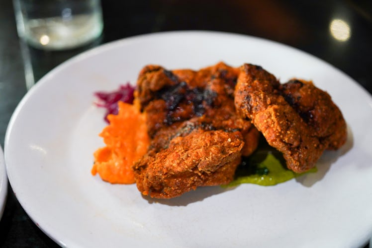 A white plate of masala fried chicken is at a restaurant in Mexico City.