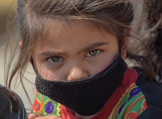 A young girl wearing a facemask amid concerns over the spread of the COVID-19 novel coronavirus sits...