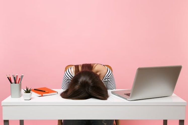 Young frustrated exhausted woman laid her head down on the table sit work at white desk with contemp...