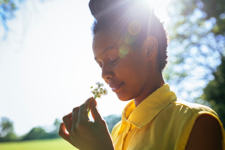 Portrait of smiling young woman smelling flowers