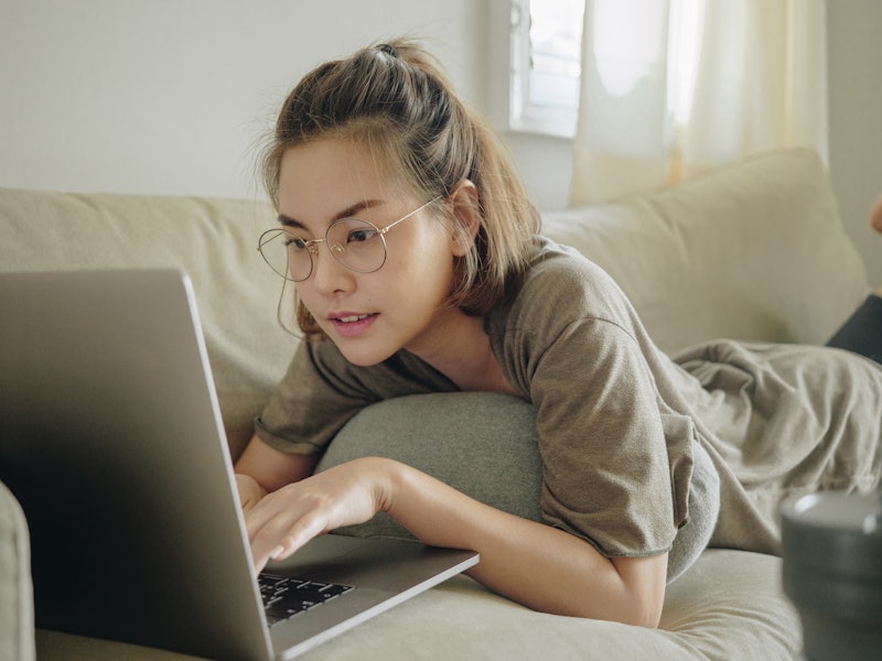 A woman works from home, typing on her laptop while lying on the couch. This article outlines how to...