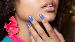 A woman posing and showing her gel nail polish purple and blue nails
