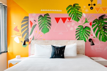 A custom mural room at Quirk Hotel in Richmond, Virginia features tropical palm leaves and bright co...