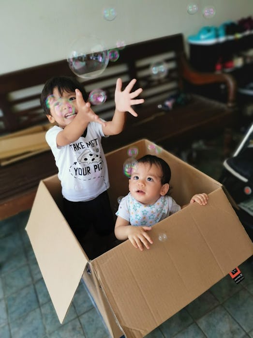 Children catch bubbles inside a cardboard box