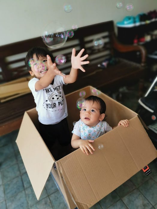 Children catch bubbles inside a cardboard box