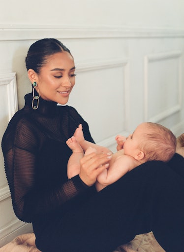 Shay Mitchell holding her baby in her lap while wearing St. John top, pants; Hanro slip dress, Sylvi...