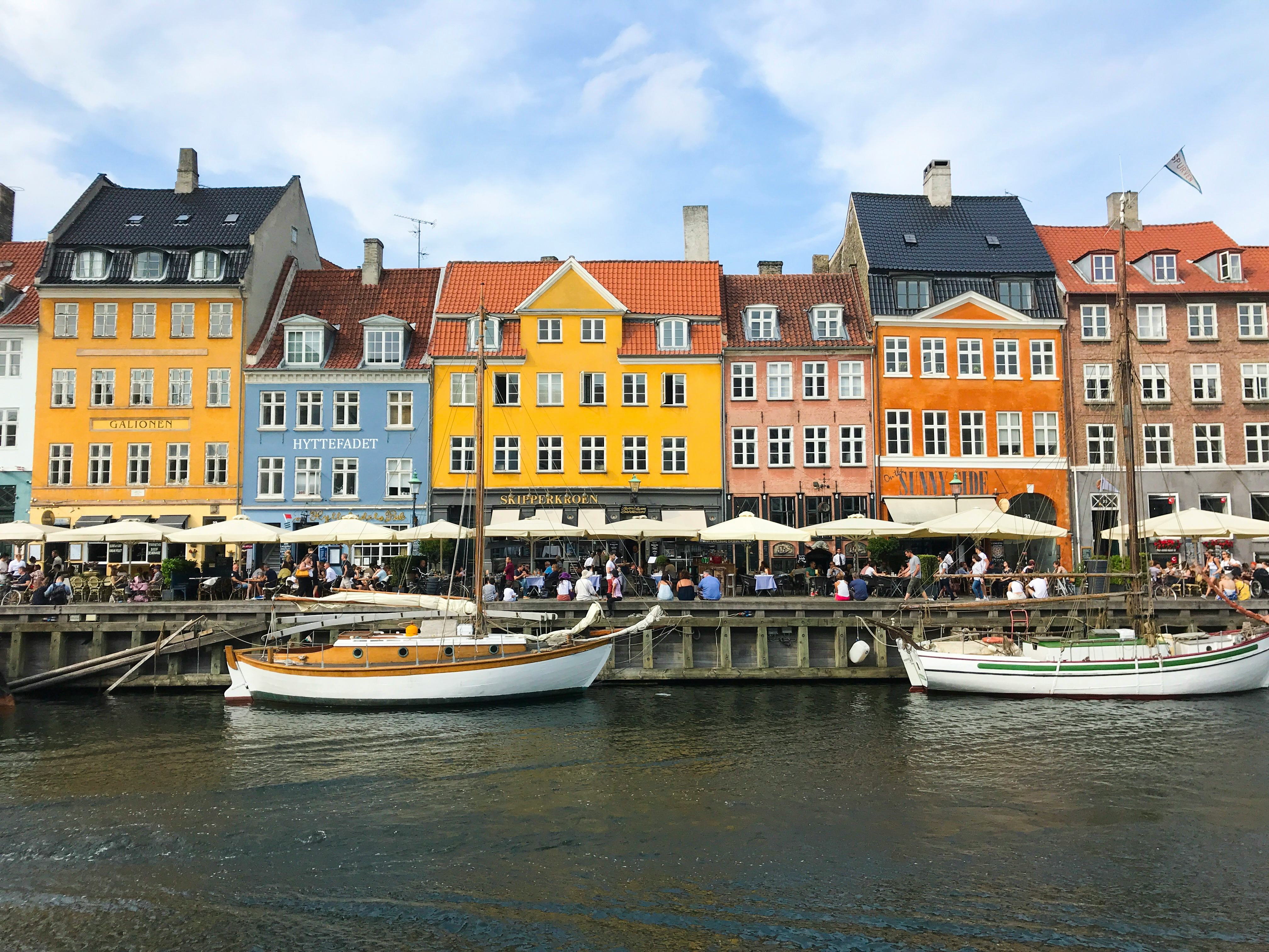 A row of colorful buildings overlooks a canal with boats in Copenhagen, Denmark.