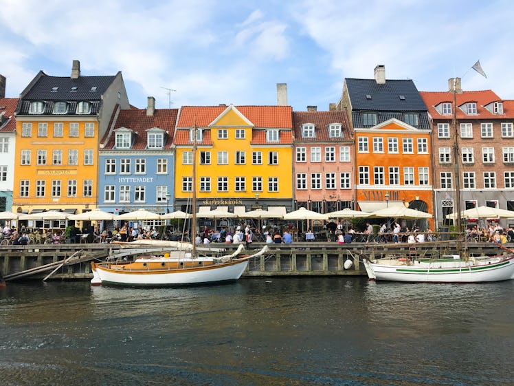 A row of colorful buildings overlooks a canal with boats in Copenhagen, Denmark.