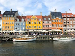 A row of colorful buildings overlooks a canal with boats in Copenhagen, Denmark.