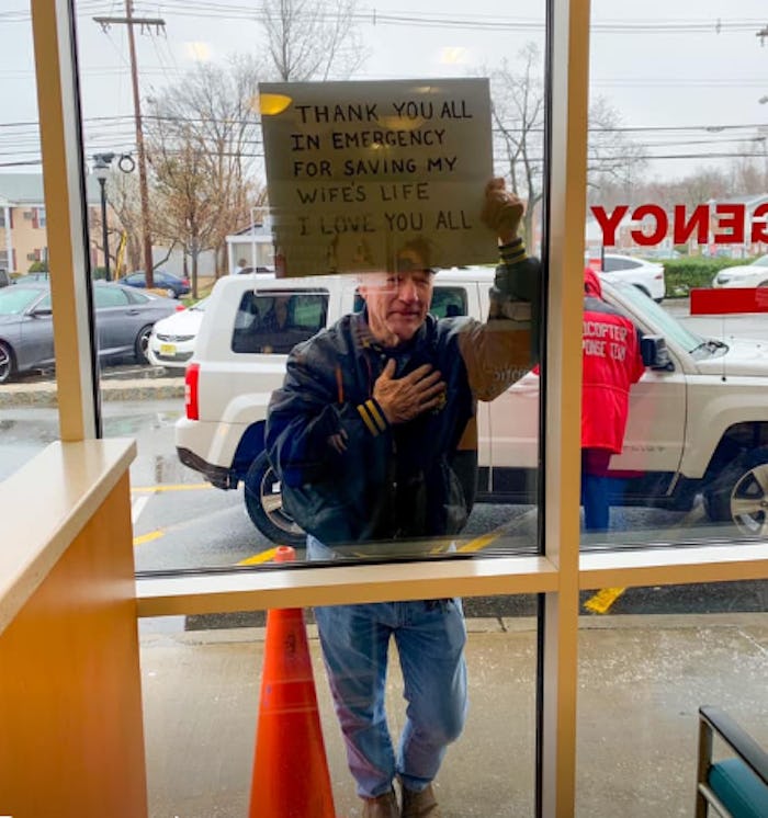 A man thanked healthcare workers for saving his wife by holding a sign up through a glass window.