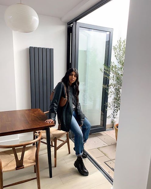 A fashion insider leaning on her table while wearing a leather jacket and jeans