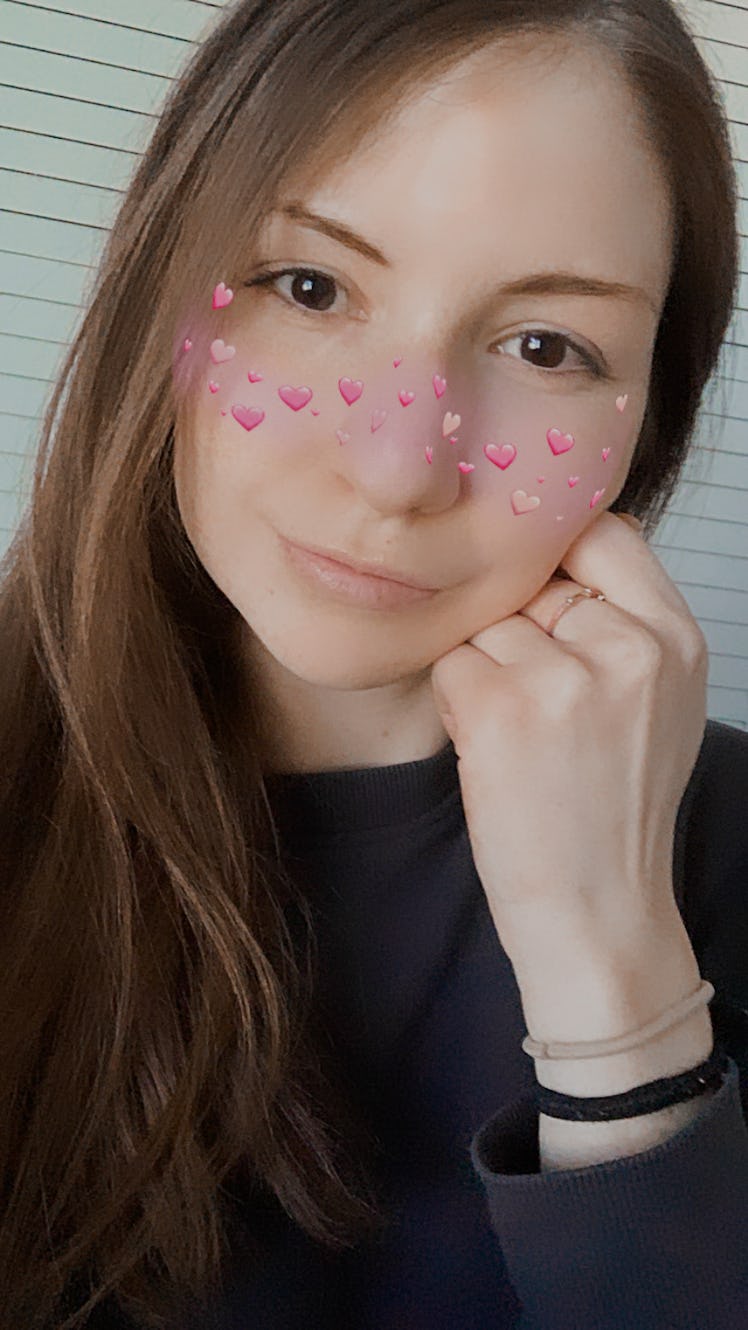 A young woman poses with an Instagram filter that puts hearts over your cheeks.