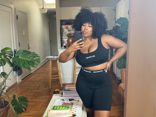 A curly woman taking a selfie in black activewear for working from home