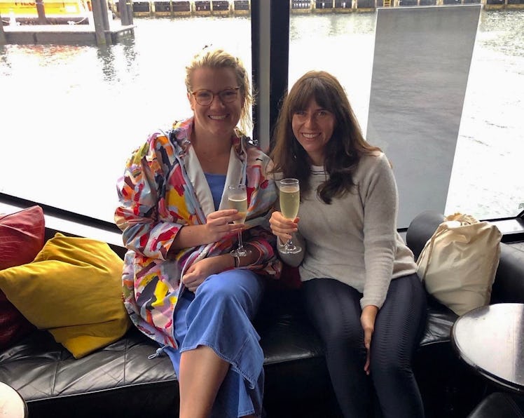 Two women sit on a boat with their champagne flutes.