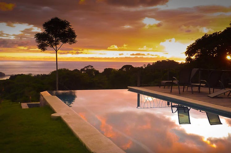 A pink and orange sunset reflects in the Airbnb with infinity pool in Costa Rica.
