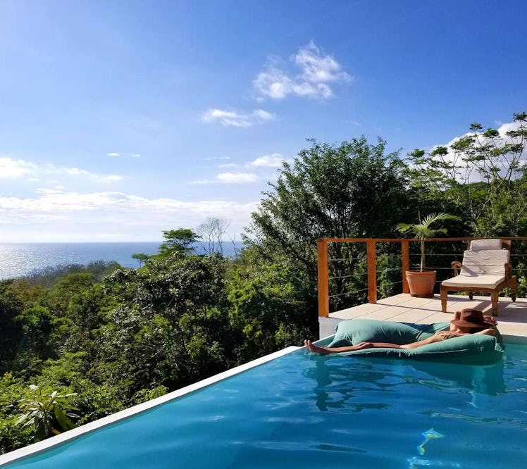 A woman lounges in the infinity pool of an Airbnb rental in Costa Rica.