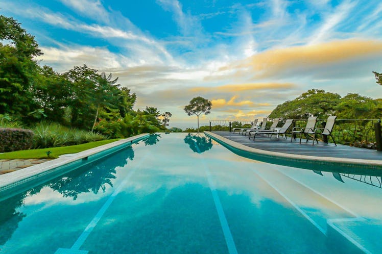 An airbnb in Costa Rica has an infinity lap pool surrounded by trees and bushes. 