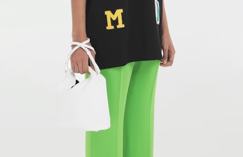 A model in green pants with a black sweater holding a white MM6 Maison Margiela's Japanese Nanobag