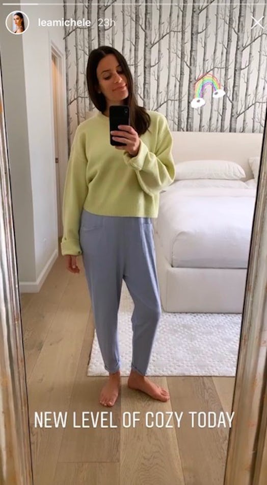 Lea Michele posing in a yellow sweater and grey sweatpants