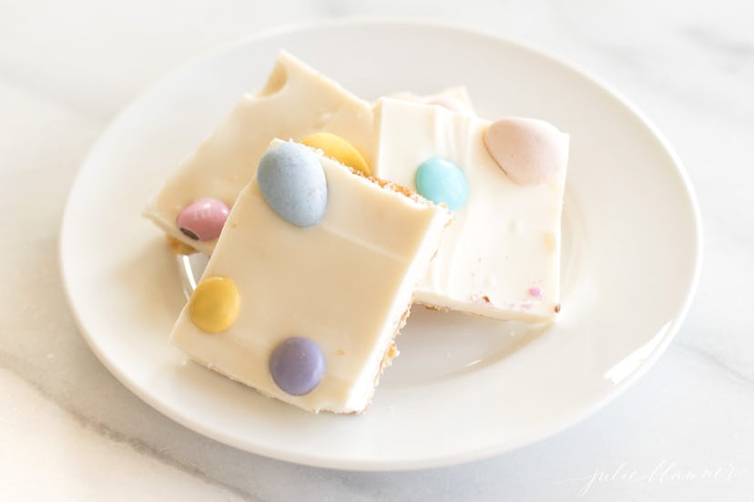 white plate with three pieces of toffee topped with white chocolate and candy eggs