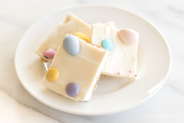 white plate with three pieces of toffee topped with white chocolate and candy eggs