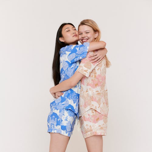 Two women hugging while wearing matching pajamas, one being blue while the other is pink
