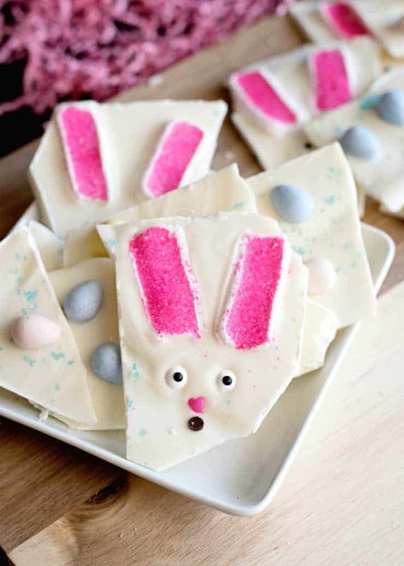 A plate of broken up pieces of white bark with easter candy and bunny faces in it