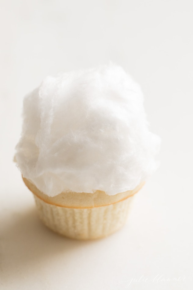 Single white cupcake topped with fluffy cotton-like topping 